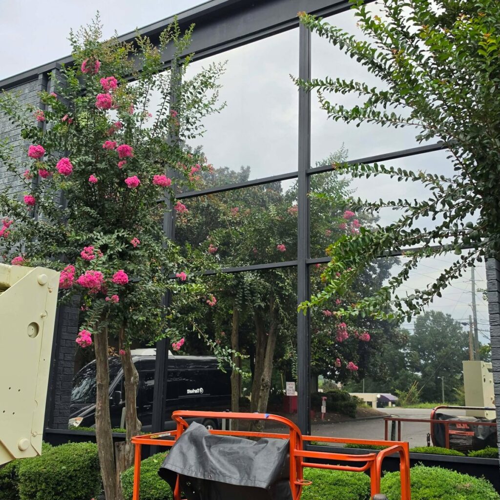 Window film installation on a tall commercial glass curtain wall, with a lift on site