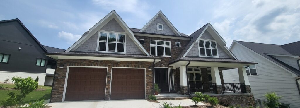 Two-story craftsman-style home with stone and gray shingle siding and window film by Solar Sentinel in Marion County, TN